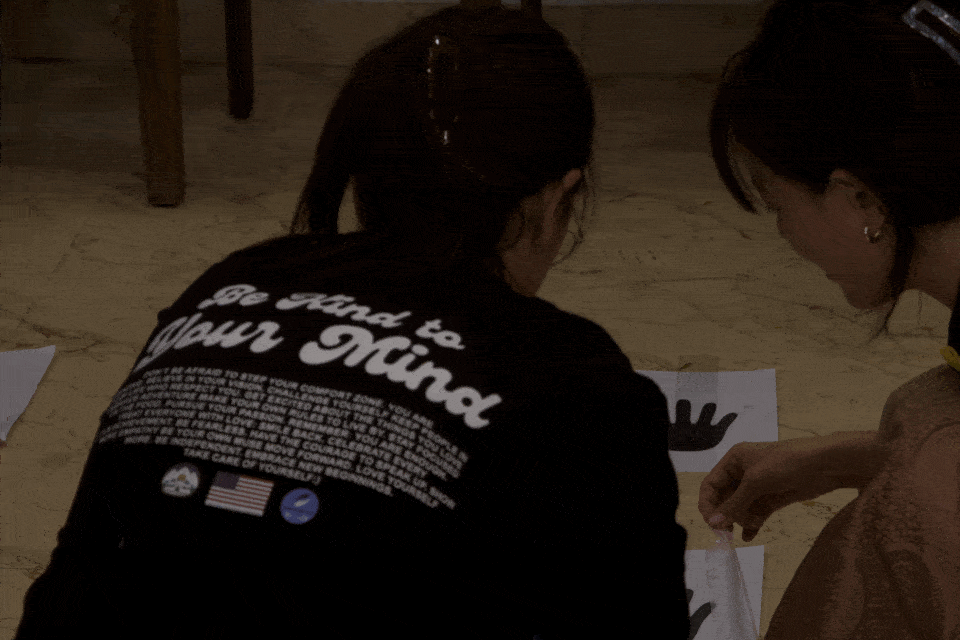 Two young people writing and reflecting together at a “Be Kind to Your Mind” workshop.
