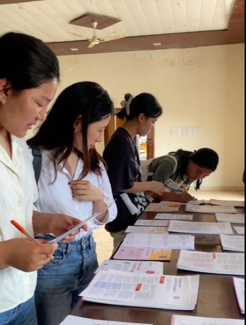Young people reading printed mental health resource handouts laid out on a table at a Chisem workshop.